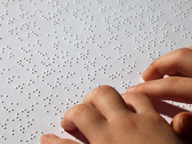 Fingers reading a page of Braille text
