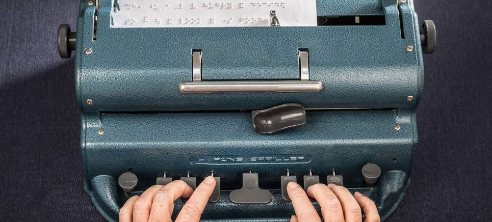 Hands typing on a Perkins Braille typewriter